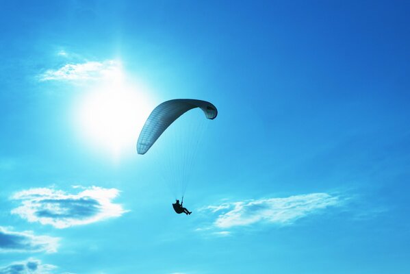 A full-screen photo of a parachutist in flight. An open parachute in the sky