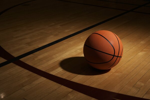 Pallone da basket all ombra sul pavimento