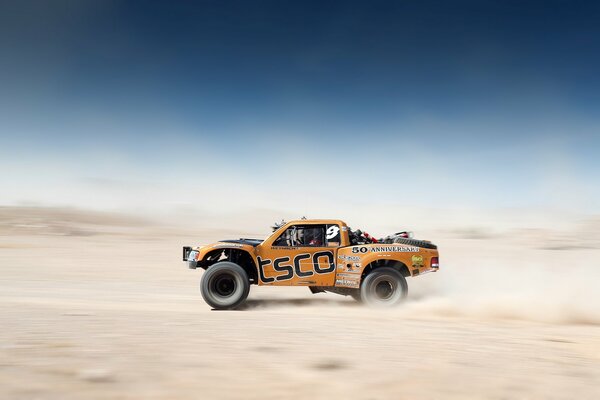 Orange pickup truck racing through the desert is beautiful