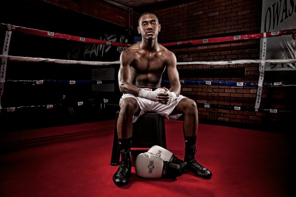 Boxer à la peau foncée assis sur le Ring