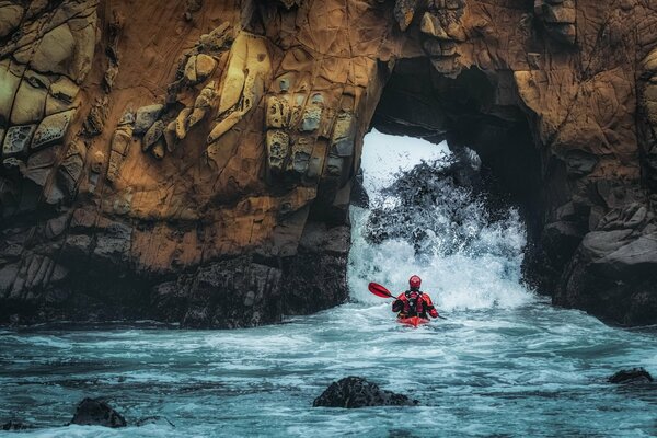 Atleta rafting su una barca attraverso le rocce