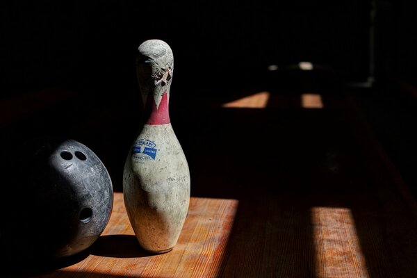 Dark room, light from the window illuminates the ball and bowling pin