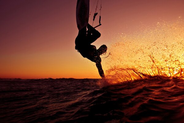 El salto de un surfista en medio de una puesta de sol