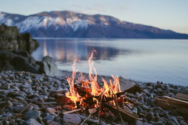 Lagerfeuer auf Kieselsteinen am Bergsee