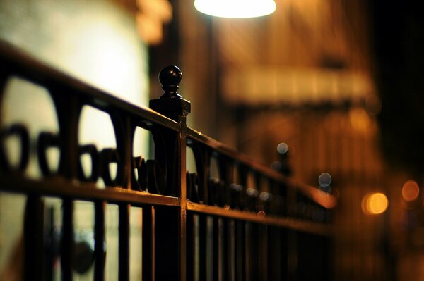 An iron fence lights up a lantern at night