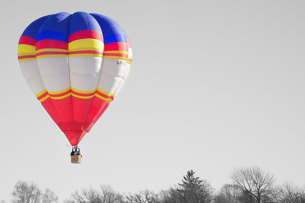 Der Ballon schwebte am Himmel über den Bäumen