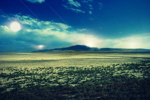 Durch die Wolken sieht man die Sonne und in der Ferne nur die Berge