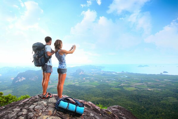 A girl with a guy with backpacks traveling in the mountains