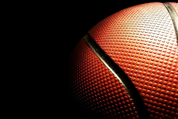 Superficie texturizada de la pelota de baloncesto en la oscuridad