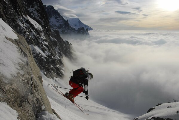 Der Abstieg des Skifahrers vor dem Hintergrund der Berge und der Sonne