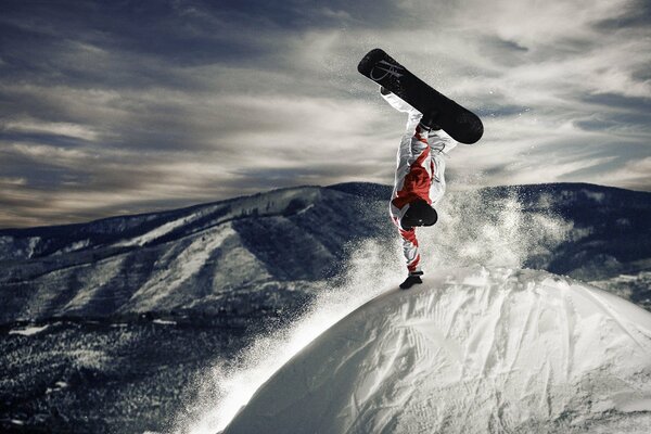 Stunt snowboarder sur un sommet enneigé