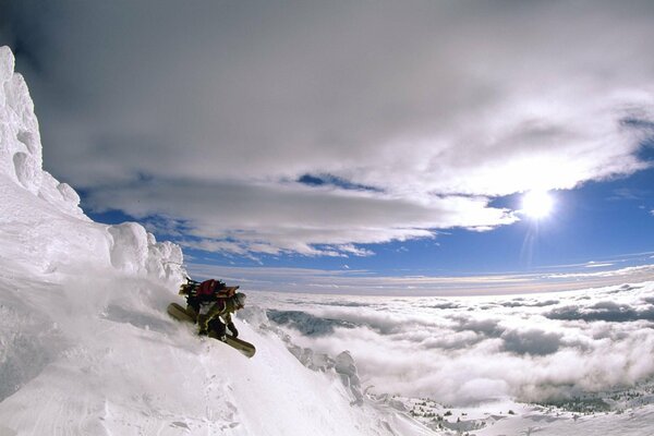 Snowboarder sur un sommet de montagne dans les nuages