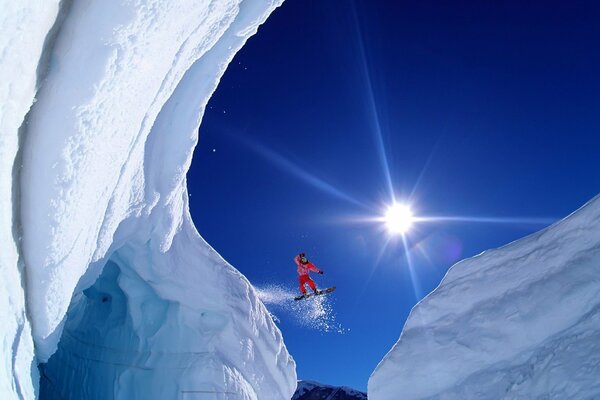 Snowboarder volando entre las montañas nevadas