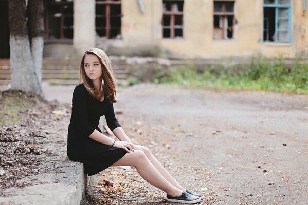 A young lady on the background of an abandoned house