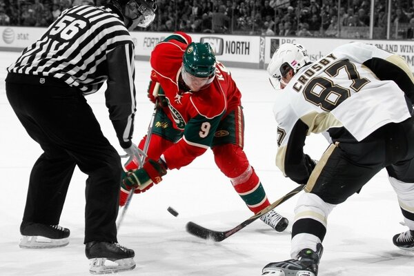 Los jugadores de hockey con palos en el hielo juegan al hockey