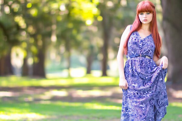 Pelirroja chica en vestido púrpura en el parque