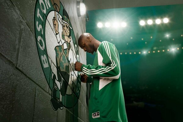 Basquetbollrst con uniforme verde reza ante el emblema del Club