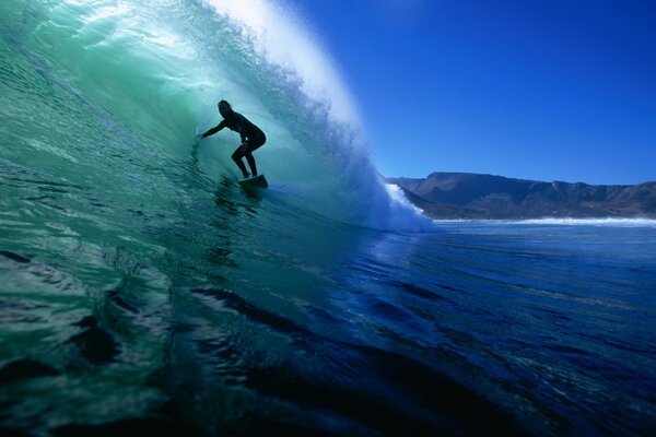 Surfista bajo la ola del océano azul