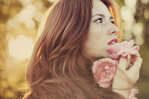 A girl with summer freckles with flowers in her hands