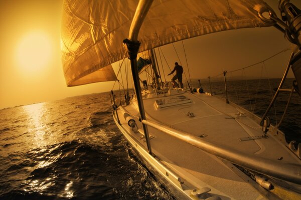 Homme sur un voilier en haute mer et coucher de soleil