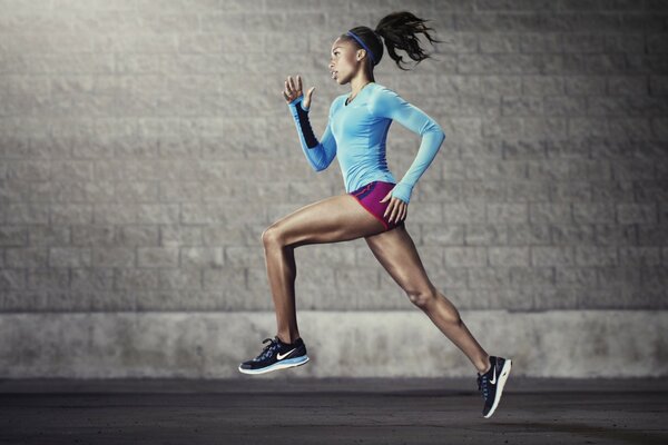 A track and field athlete in a blue jacket runs