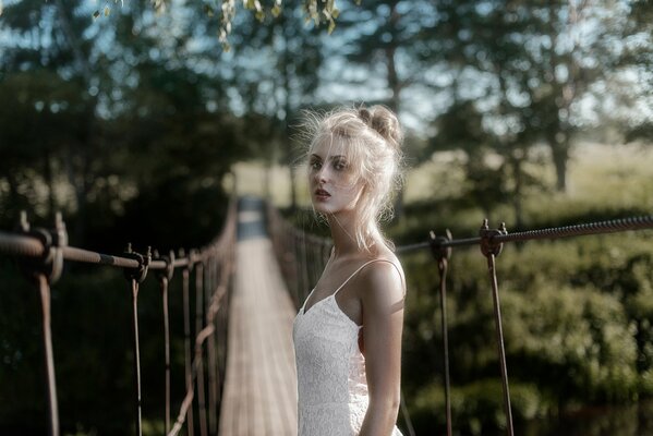 A girl on the background of a rope wooden bridge