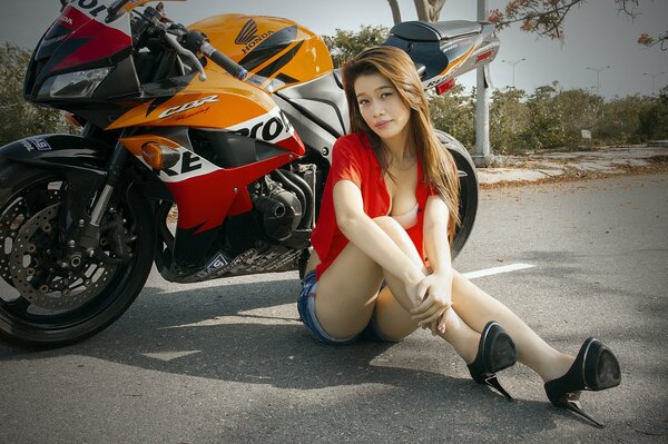 Asian woman posing on the background of a motorbike