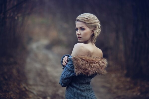 Blondine in einer Jacke mit Fell auf nackten Schultern