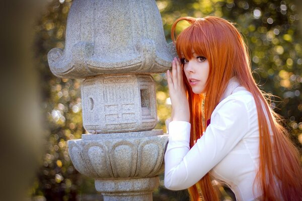 Beautiful red-haired girl in the park next to the monument