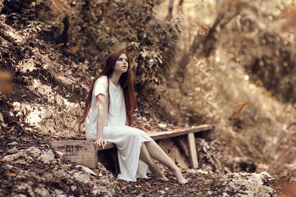 A girl on a bench in the autumn forest