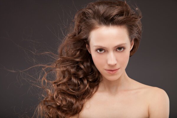 La mirada de los ojos marrones de una chica con cabello ondulado