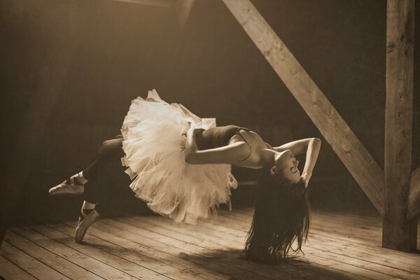 A ballerina in a white tutu and black stockings levitates in the attic