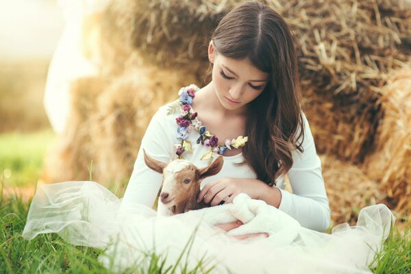 A girl with freckles strokes a goat