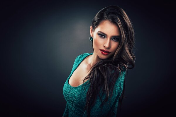 Brunette in a green dress with a large neckline on a dark background