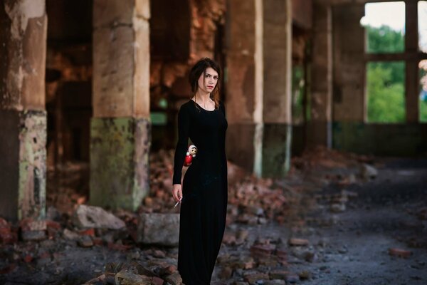 Jeune fille en robe noire avec des cheveux bruns avec gireta dans les mains sur le fond d un bâtiment abandonné