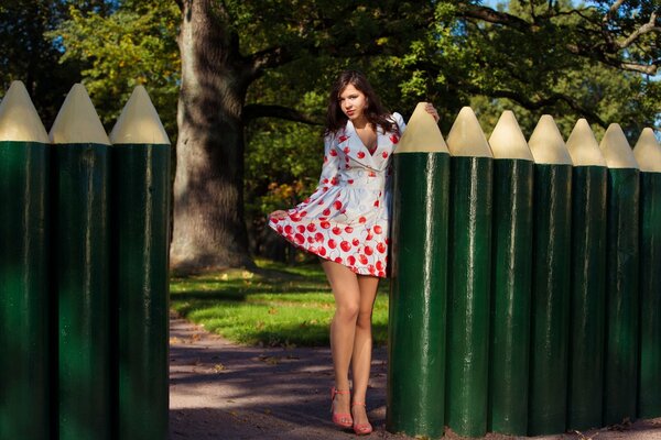 The girl is standing near the fence