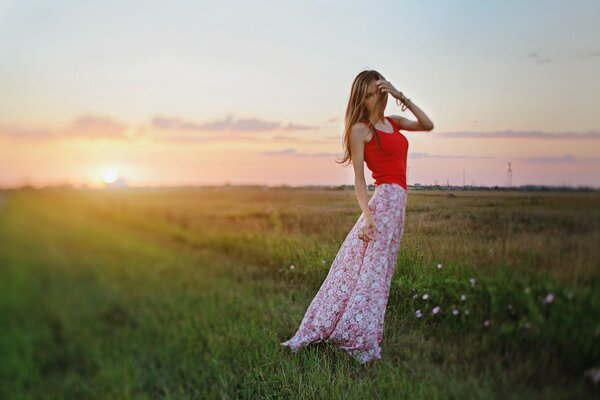 A girl in a long skirt against the sunset