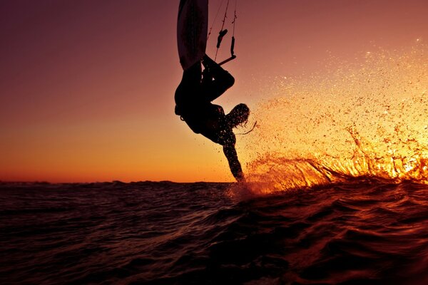 Surfeur sur la vague au coucher du soleil