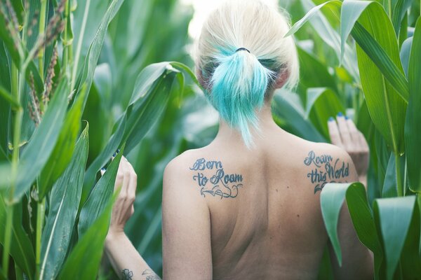 Chica con tatuaje y cabello verde en un campo de maíz