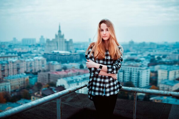 Chica con camisa a cuadros en el fondo de la ciudad