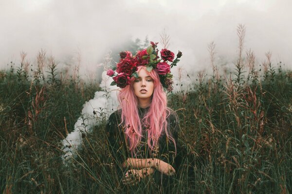 Mädchen mit rosa Haaren und einem Kranz aus hellen Blumen auf dem Feld