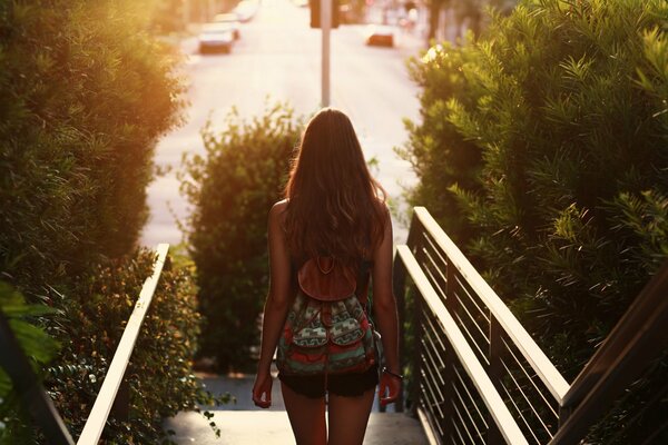 Fille aux cheveux longs avec un petit sac à dos sur le dos