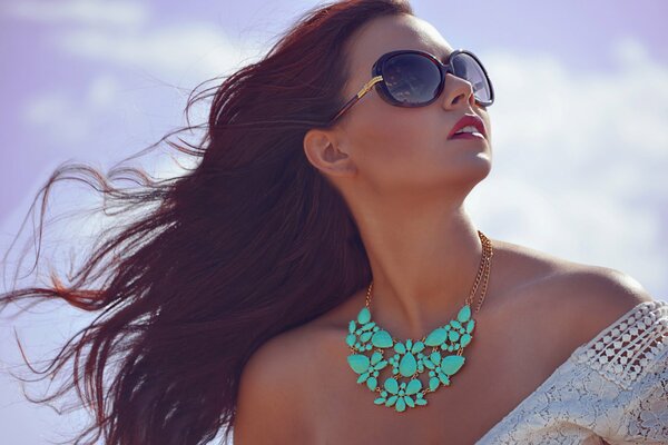 Una chica con gafas de sol y un adorno en el cuello