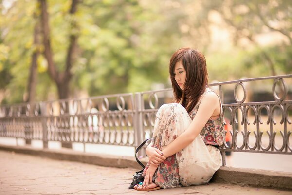 Asiatische Mädchen sitzt nachdenklich im park