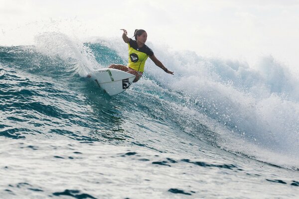 Chica corta a través de las olas en el surf