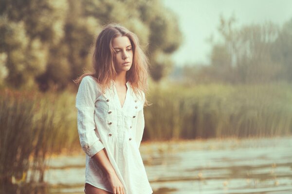 Chica triste con una blusa blanca en el fondo de un estanque