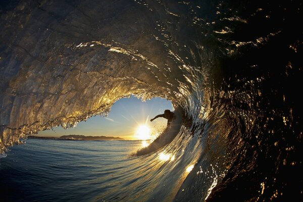 SURFER wewnątrz fali o zachodzie słońca