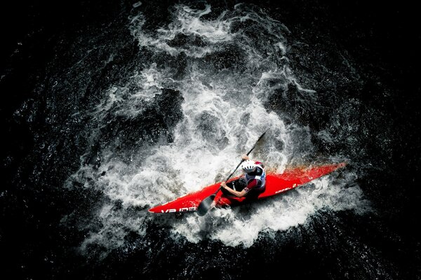 A man in a sports boat with one paddle floats on the water