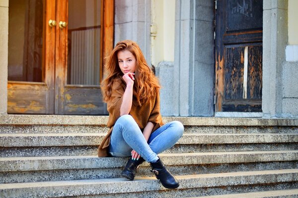 A red-haired girl is sitting on the steps