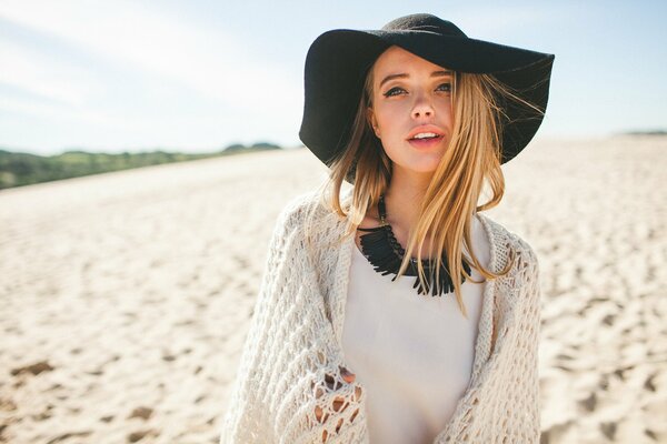 Fille au chapeau noir sur fond de sable blanc